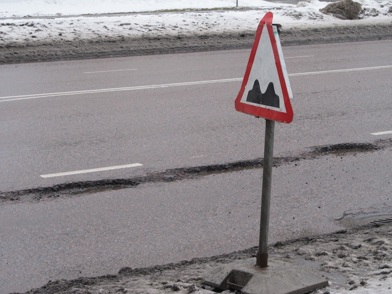 What does the road sign mean? Ettevaatust, kaks muhku teel? – Attention, two bumps in the road ahead? Or brace yourself for a kraater? It actually means be ready for anything; rough roads, i.e surprises ahead. Surprises that were not there yesterday. In this case, a trio of potholes in the alfaldist tee/kate (asphalt pavement or road surface), which looks to be just the right size to swallow your tire perfectly and give you a terrific jolt, i.e. the term löök/auk – "strike hole". Photo: Riina Kindlam