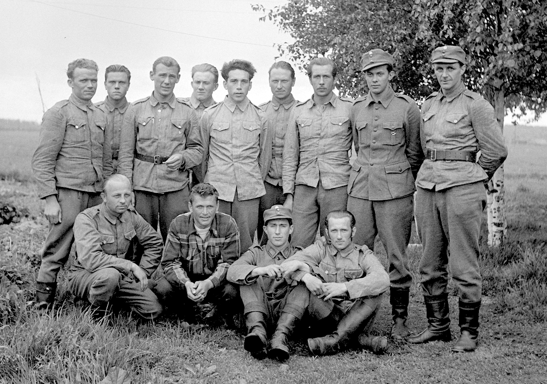 Foto on tehtud 10.06.1942 Nurmoilas, kus asus kaugluure keskus. Esimene rida vasakult: 1.Täheste, Rudolf 2. Karmo, Henn (?) 3. Krivain, Osvald 4. ?? Teine rida vasakult: 1.Veebel, Artur (?) 2.Pedanik, Helmut (?) 3. Tartu, Hugo 4. Ruberg, Endel (?) 5. Rägastik, Artur 6. ?? 7. ?? 8. Randmäe, Voldemar (?) 9. Jürgens, Karl