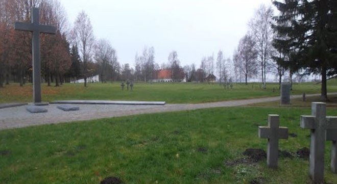 Maarjamäe saksa sõjakalmistu üldvaade. Pildil vasakul nimekivide väljak. Paremal pool kuuse okste all on kalmistu väravakivi. Rühmiti, kolme madala ristiga, on märgistatud kogu kalmistu väli ja nurgad. Taamal paistavad Eesti Ajaloomuuseumi hooned ja tükike Tallinna lahte. Foto J. Haud erakogust. 