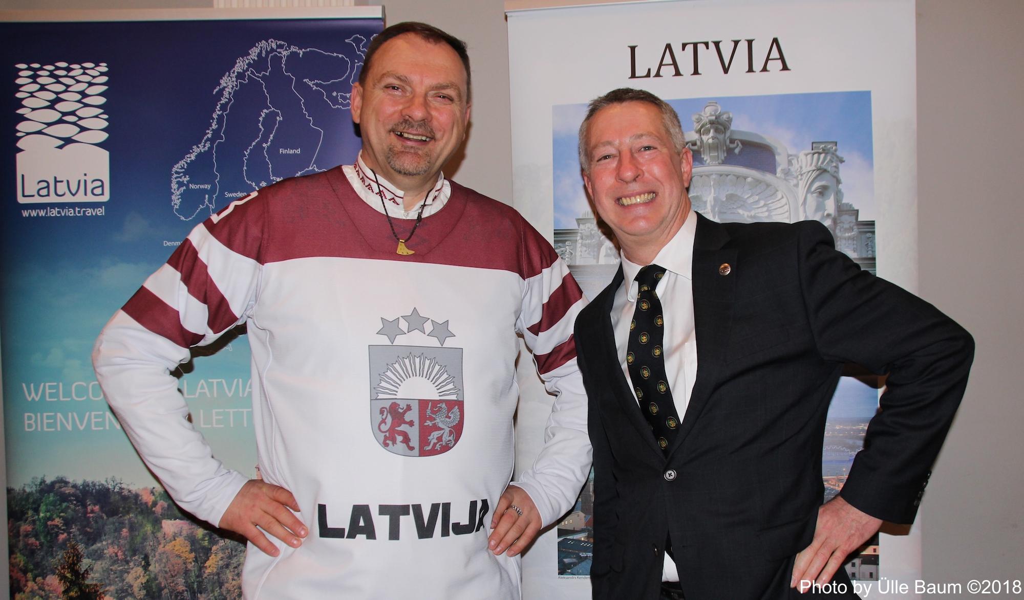 Fotol vasakult: Lieutenant Colonel Agris Ozolinš, Defence, Military, Naval and Air Attaché ja Marks Deitons, Läti Suursaatkonna 1. sekretär Läti turismiplakati ees. Foto: Ülle Baum ©2018