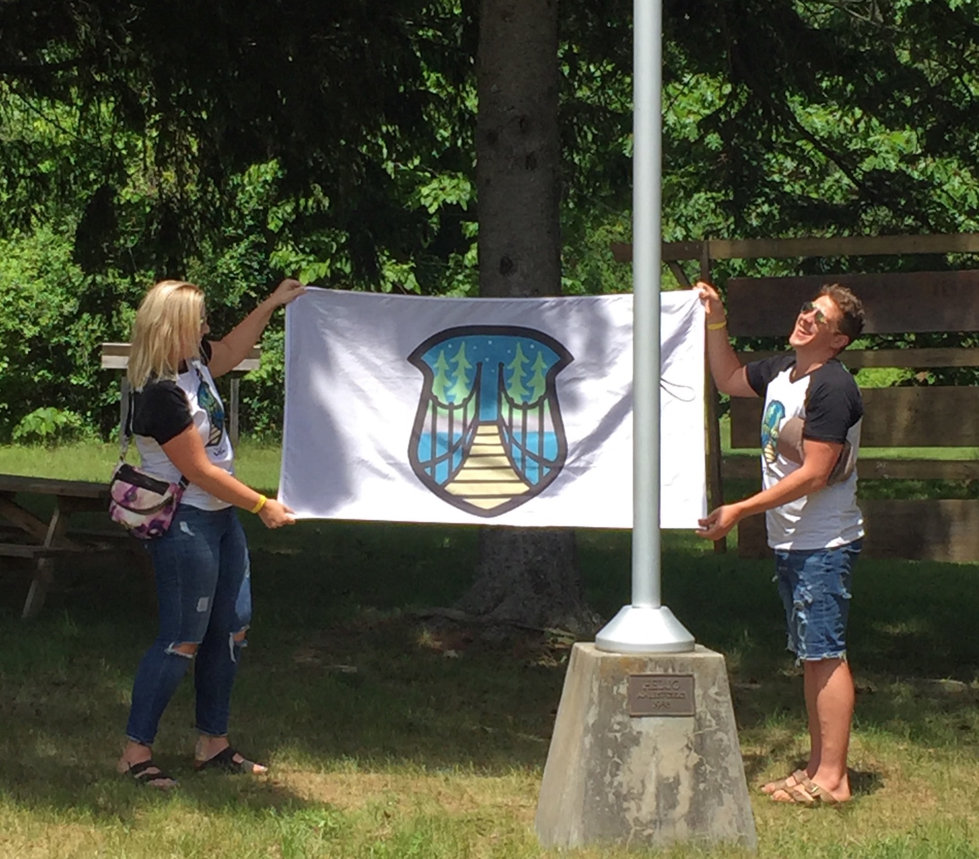 Two of the inaugural „JK Alumni Laager“ (JKAL) organizers, Anneliis Põldre and Paul Lillakas, show off the brand-new JKAL flag with its custom logo, designed by Ashley Lennox. Photo credit: Kristina Põldre (2018)