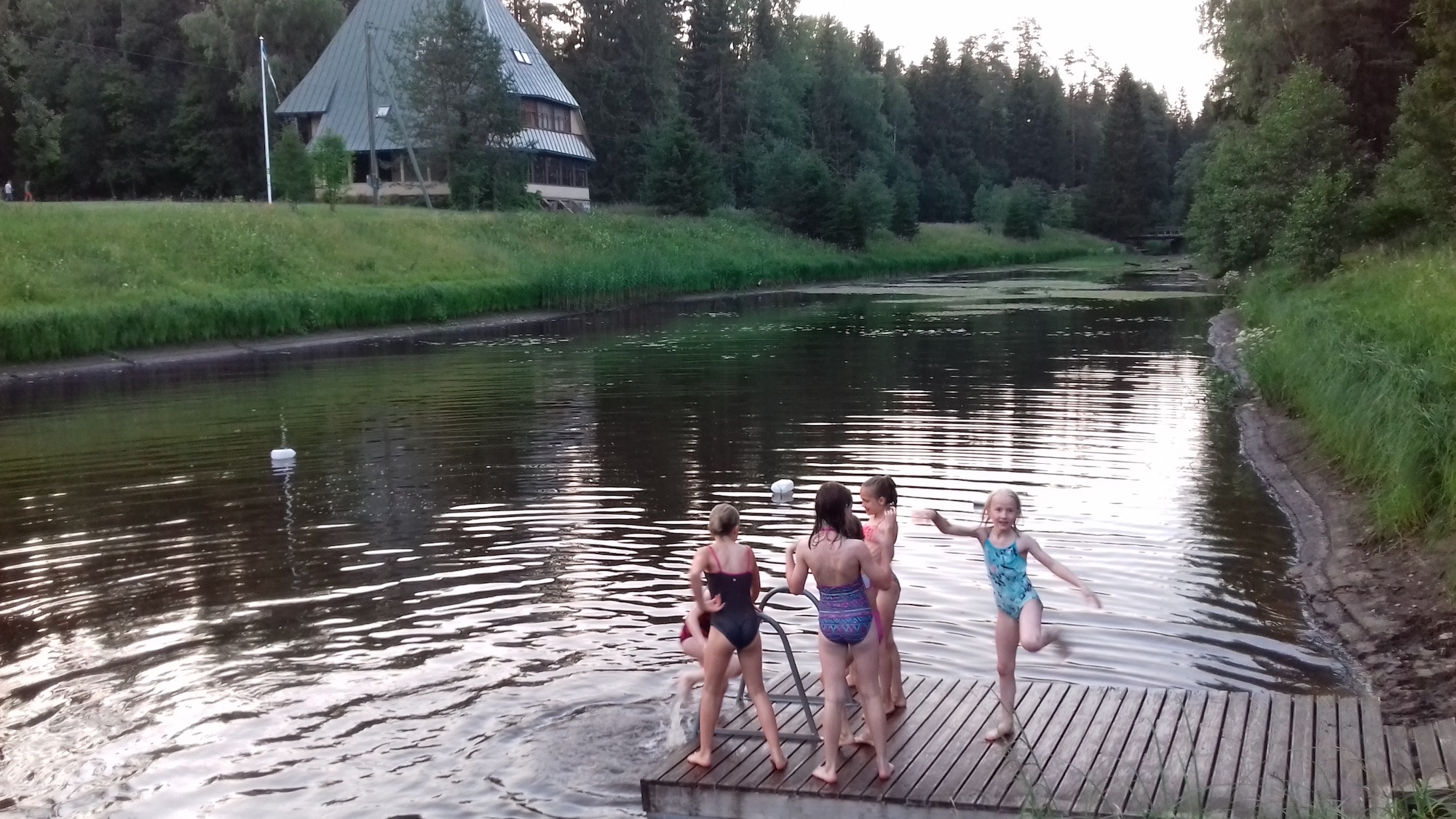 Eesti Kotkajärve on Tagametsa, mis asub Türi linnast törtsuke lõunas, Rassi küla lähedal. Kotkajärve asemel on siinsetel lastel Saarjõgi. Sellel fotol, mis tehtud 16. juulil oli veel veetase enam-vähem, olgugi et ujumissild langes kaldalt pea 45 kraadi alla veeni. Juba järgmisel päeval oli vett juba 10 cm vähem, muuhulgas kuna sillaalune tamm, mis jääb fotograafi selja taga, laseb veidike läbi. Aga vihma pole ka ammu enam nähtud. Ega see olukord (k.a. meeletud rannaparmud) palavuse käes vaevlevaid hundusid muidugi heiduta, lihtsalt tuleb pärast pesumaja jääkülma dušši all naba korralikult mudast puhtaks pesta. Taamal paistab Tagametsa jahiloss, siinne peamaja. Foto: Riina Kindlam (2018)