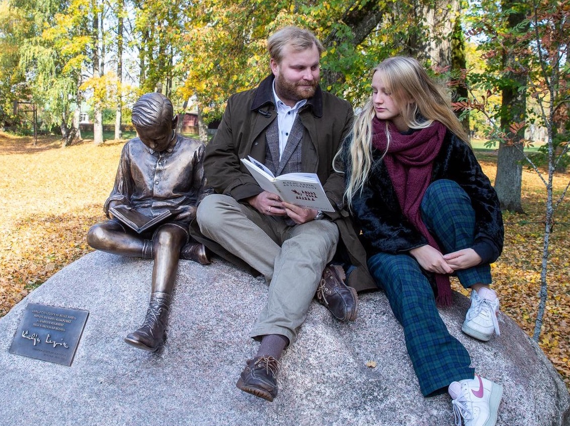 Oma vanaisa, luuletaja Kalju Lepiku kuju kõrval istuvad tema tütrelapsed Illimar ja Mari Lepik von Wirén. Paremal taga paistab Lepiku loomingu üks sümboleid, sinna istutatud pihlakas. Foto: Ants Leppoja / MTÜ Järvamaa Eesti Südamaa (2020)