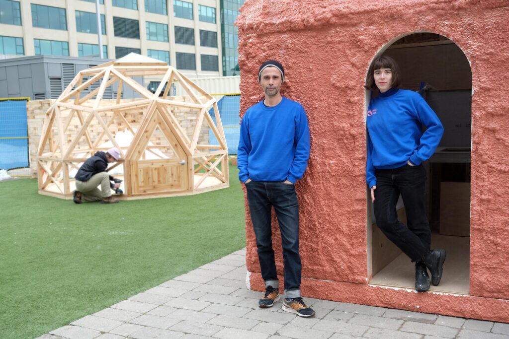 Co-curators Rui Pimenta and Layne Hinton during the build of Public Sweat in front of a sauna by SHEEEP with a geodesic dome by Christie Pearson in the background—photo courtesy of Art Spin