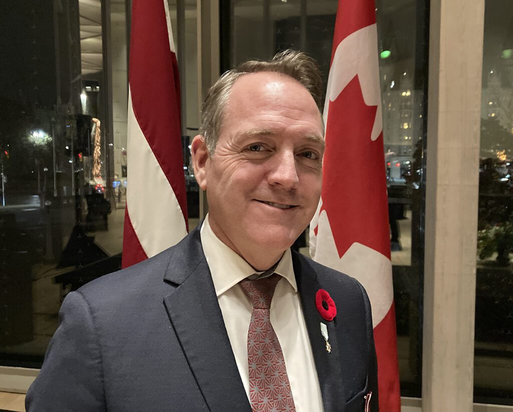 Kevin Rex, Director General, Security and Emergency Management - Strategy & Policy (CED), Global Affairs Canada esindaja ja endine Kanada suursaadik Lätis, Leedus ja Eestis  seisab uhkusega Kanada ja Läti Vabariigi lippude keskel. Foto: ©Ülle Baum