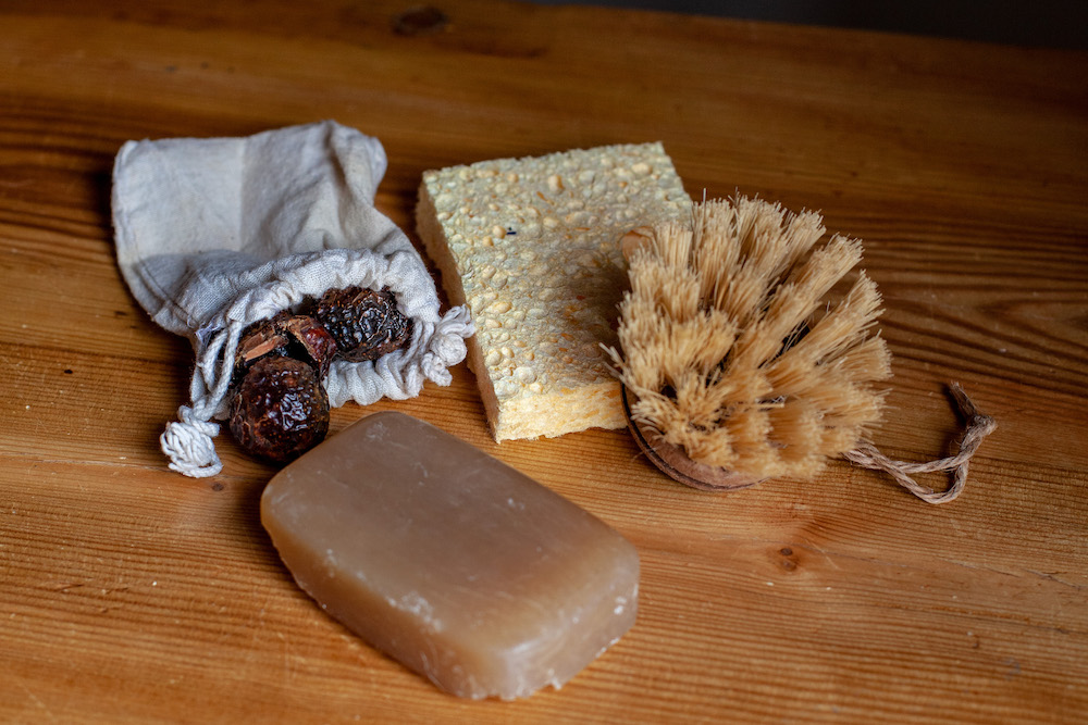 Dried soap berries/nuts, natural sponges and brushes, cleaning soap — natural plastic-free items that help keep your home and laundry clean.