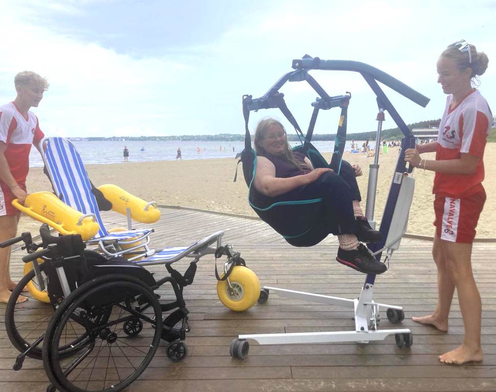 G4S coastal rescue team members transfer a visitor of Pirita Accessible Beach from one chair to another using a special crane. Source: Aune Mägi