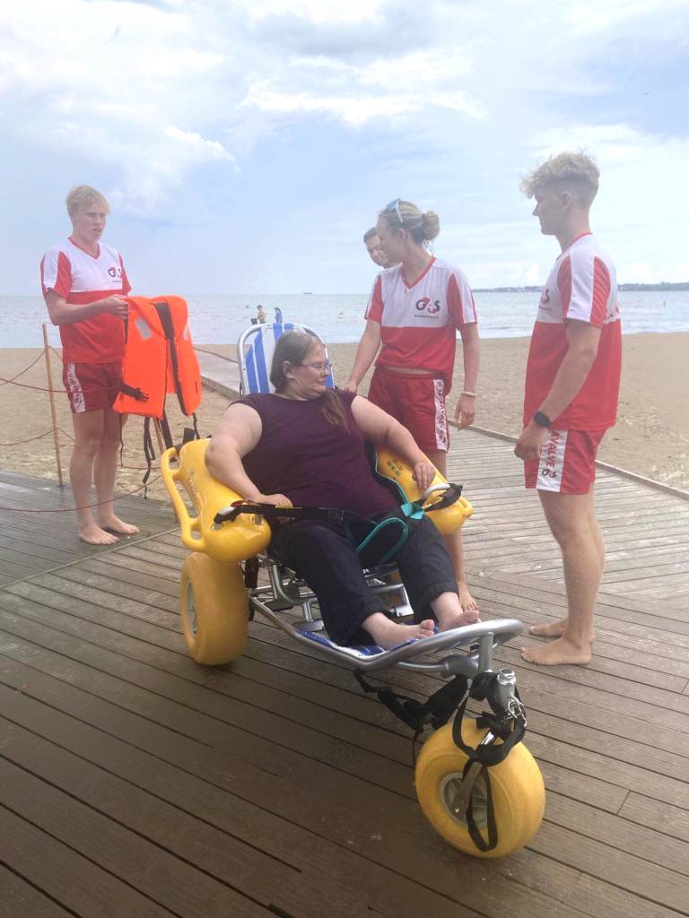 Preparing to swim in the sea in a water wheelchair, accompanied by a shore rescue team. Source Aune Mägi