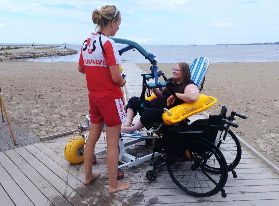 Aune Mägi and a G4S shore rescue assistant wait for another employee to move her from a water chair to a regular wheelchair.
Source: Jerry Mercury