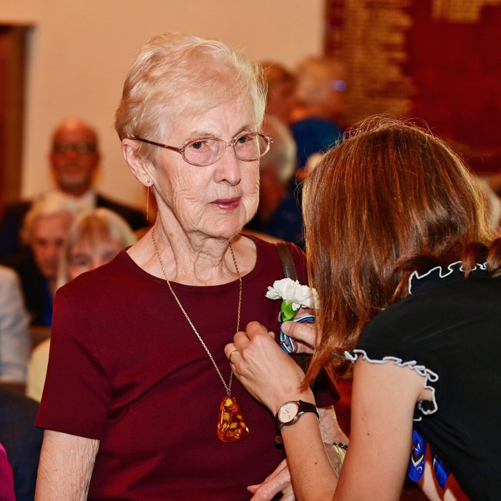 Üks kohalolnud põgenikest – Ellen Loite – saab rinda valge nelgiõie. Foto- Peeter Põldre