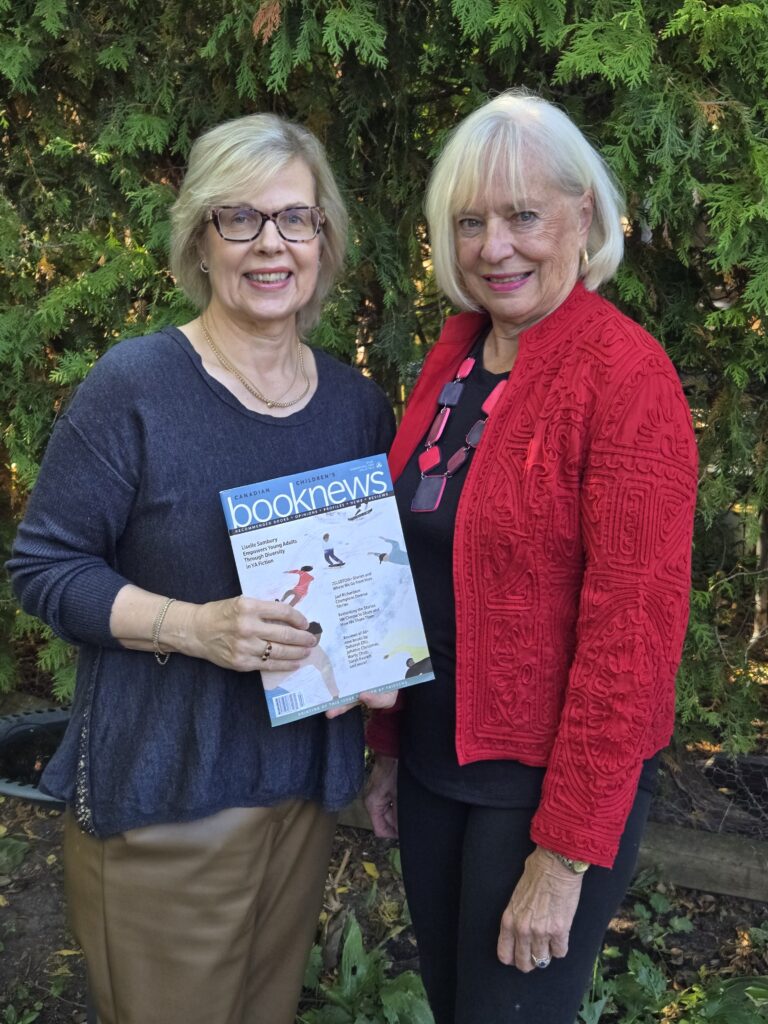 Urve Tamberg and Anne Remmel holding the latest issue of Book News in which CCBC reviews new Canadian books for all ages