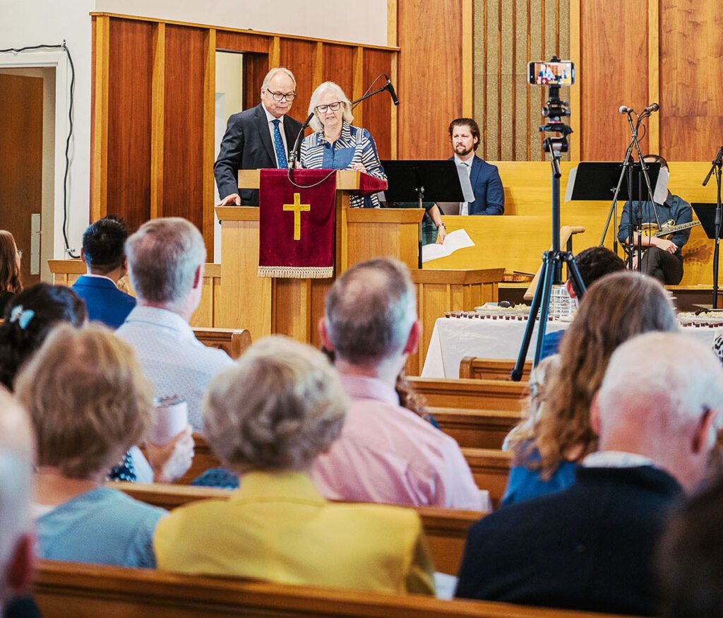 Marika ja Paul Wilbiks esitavad Toronto Eesti Baptisti koguduse ja kiriku ajalugu. Tagaplaanil istub Christ Church Toronto pastor Kyle Hackmann.