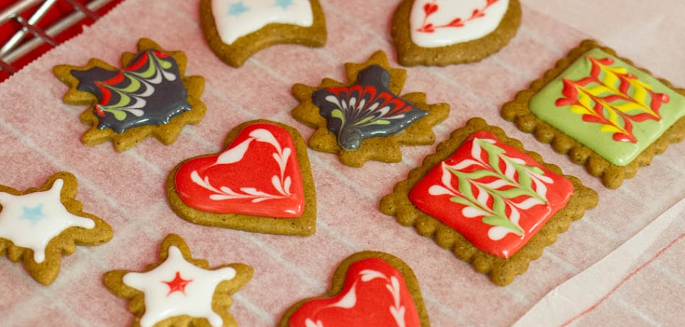 Vibrant gingerbread cookies with intricate, colourful icing designs inspired by traditional patterns, featuring hearts, stars, and floral motifs (source: PiparkoogiMaania)