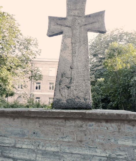 Bas-relief of the crucifixion on the Hochgreve cross, framed by summer trees. Photo: Jerry Mercury