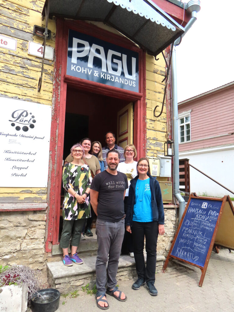 Eestisse kolinud ja inglise keeles kirjutavad WWFF (Will Write For Food) grupi liikmed väljasõidul Haapsallu tänavu 7. juunil kohviku ja raamatupoe „Pagu“ trepil. Ees: kirjanik ja tõlkija, kes peatselt Tartu College’is esineb – Adam Cullen Minnesotast; Lisa Trei (New Yorgi linnast pärit, hilisemalt Californiast), taga vasakult Riina Kindlam Torontost, Christa Peck Seattle’ist Washingtoni lähistelt, Fiona Alston Šotimaalt, Chris Springer Sacramento Californiast ja Liisa Rohumaa Dorsetist Inglismaalt. Kõik nad elavad ja töötavad Eestis. Foto: RK