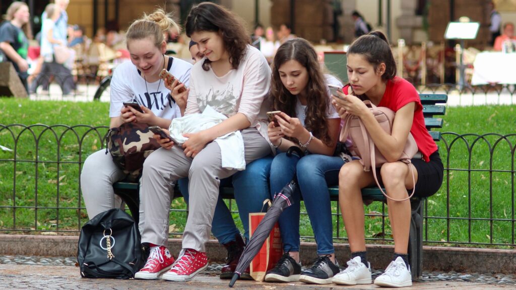 Students distracted by their phones, by GHCassel on Pixabay.
