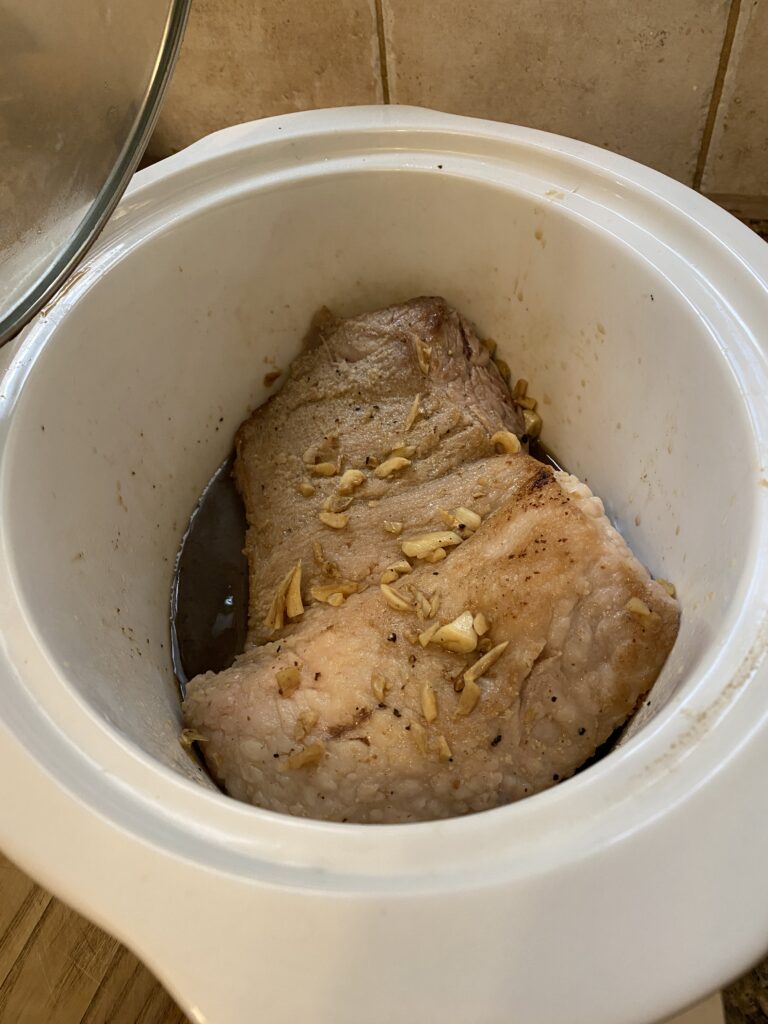 The brisket in the slow cooker just after searing